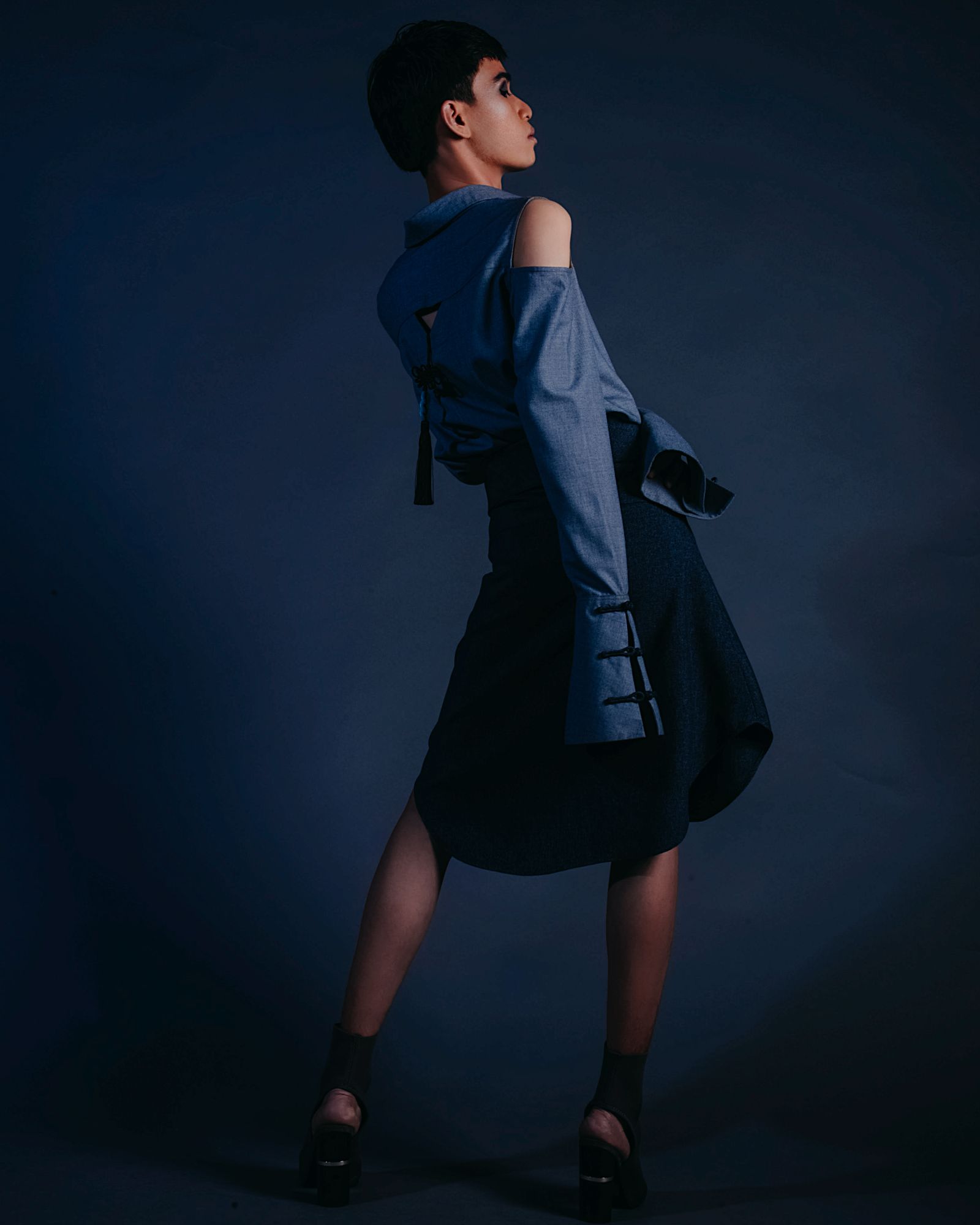 A model in an elegant outfit in a moody studio.